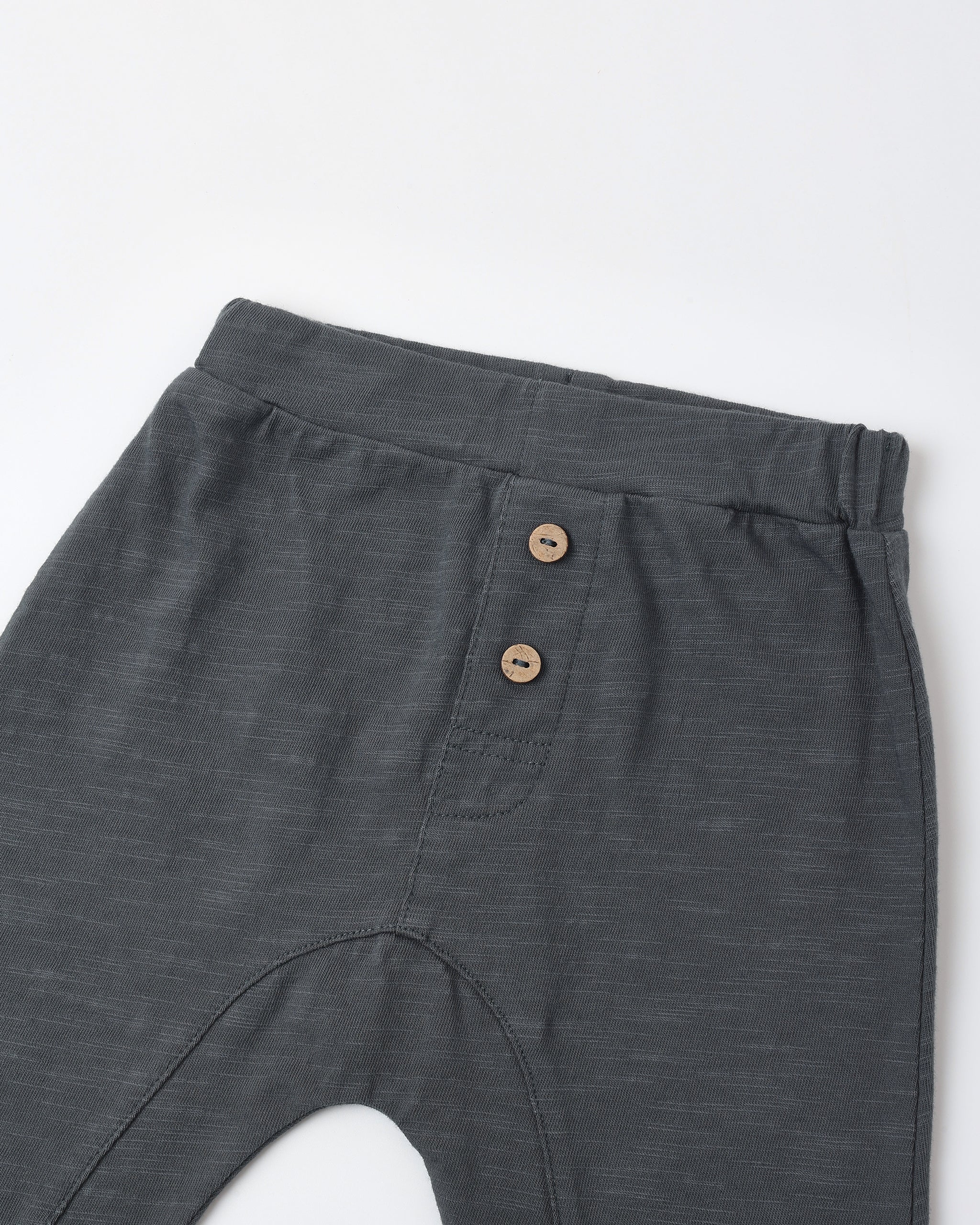 Close-up of dark gray heathered pants showing the waistband, side pocket with two brown buttons, and part of the leg on a white background.