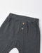 Close-up of dark gray heathered pants showing the waistband, side pocket with two brown buttons, and part of the leg on a white background.