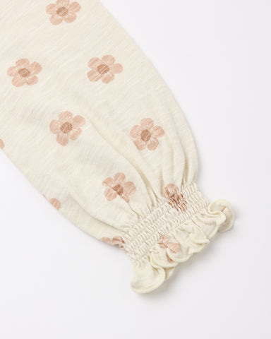 A close-up of a cream-colored fabric sleeve with a smocked elastic cuff and a repeating dusty pink floral pattern, set against a plain white background.
