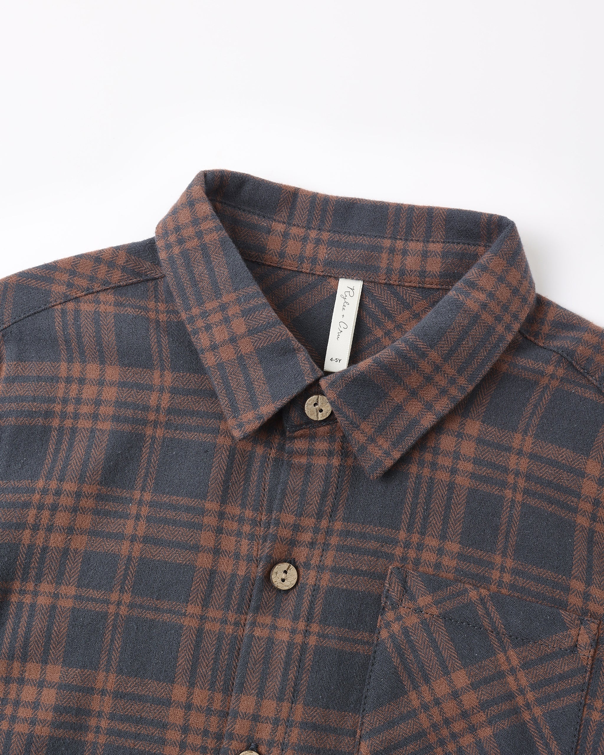 A close-up of a plaid button-down shirt collar and upper chest. The fabric has a dark slate blue-gray base with a rust brown and muted orange plaid pattern.
