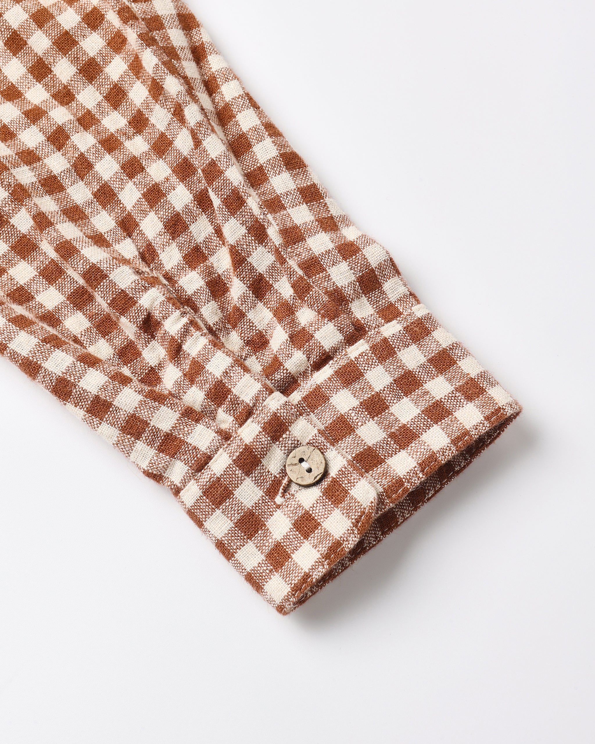 Close-up of a brown and cream gingham checkered shirt sleeve with a buttoned cuff, shown on a light gray background.