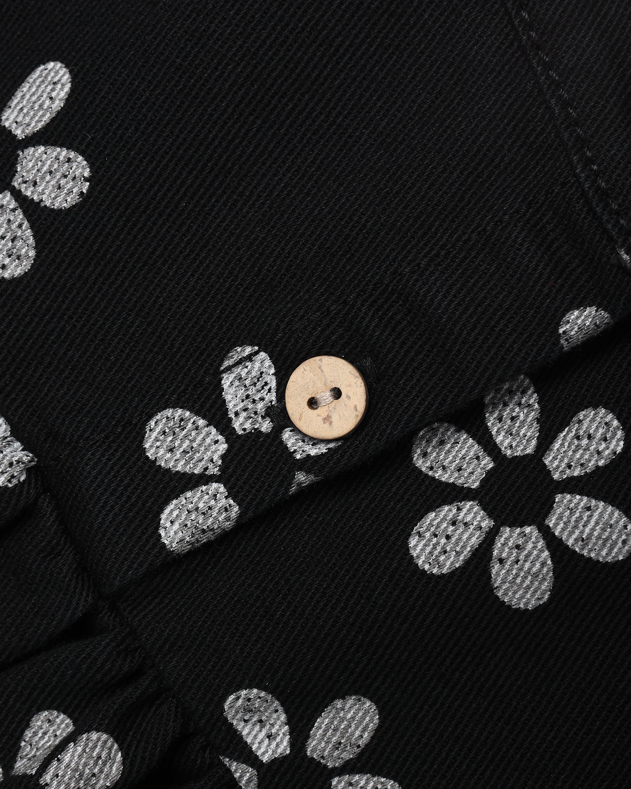 A close up of a black denim babydoll dress with a white daisy pattern 