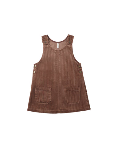 A brown corduroy pinafore dress for toddlers, featuring front patch pockets and decorative buttons on the shoulder straps and armholes, shown against a plain white background.