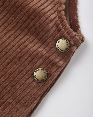 Close-up of a brown corduroy garment corner with two round brass buttons engraved with 'Cru Ayley', on a light gray background.