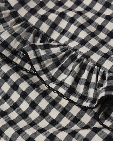 Close-up of black and white checkered fabric with a ruffled edge.
