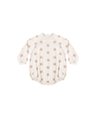 A long-sleeve Crewneck Romper in soft jersey bold pink daisy pring on a natural colored fabric designed with elastic leg openings and bottom snaps for easy changes.
