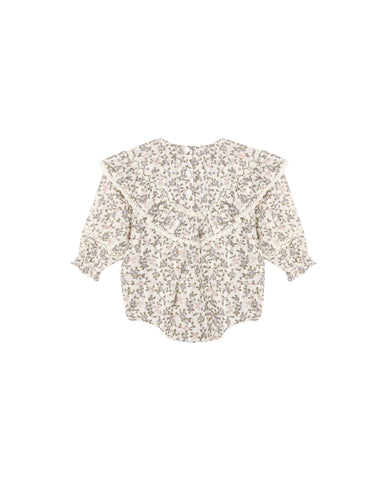 An ivory colored romper with a small floral pattern with a ruffle front shown on a white background.