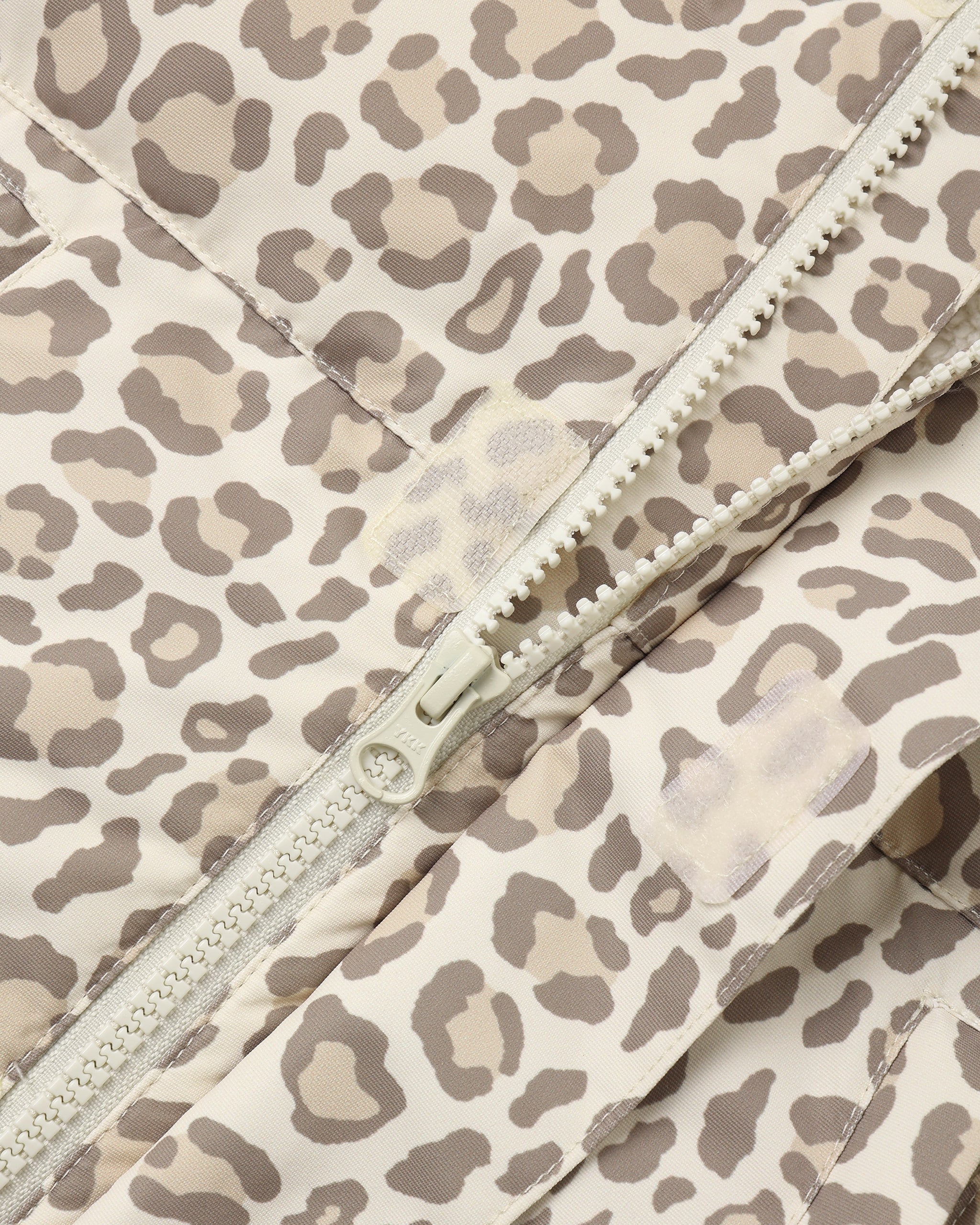 Close-up of a leopard print quilted jacket with a cream-colored zipper.