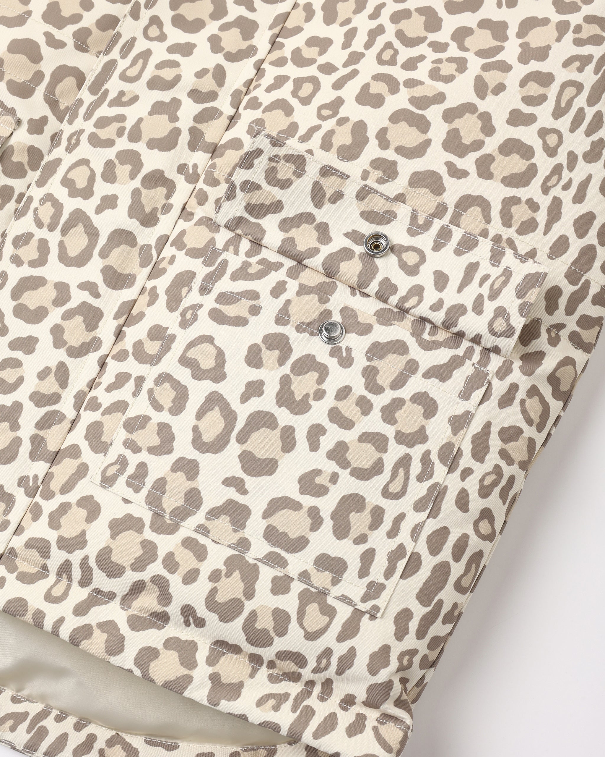 Close-up of a leopard print fabric with a matching pocket and silver snap buttons, shown against a plain light background.