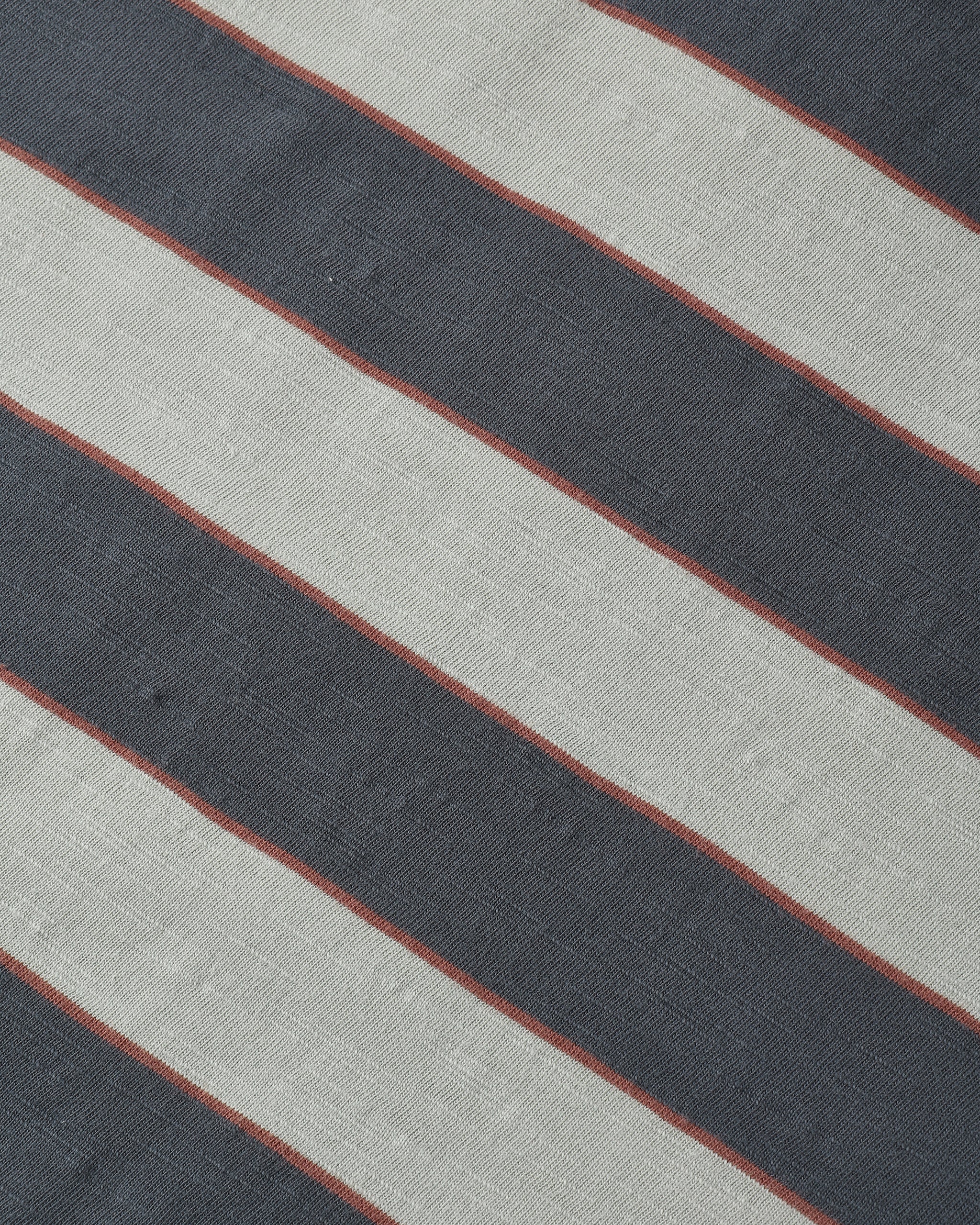 A close-up of a striped textile pattern featuring diagonal bands of dark charcoal gray, light beige, and thin rust-red lines.