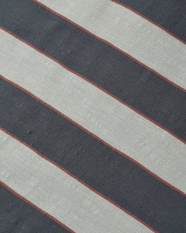 A close-up of a striped textile pattern featuring diagonal bands of dark charcoal gray, light beige, and thin rust-red lines.