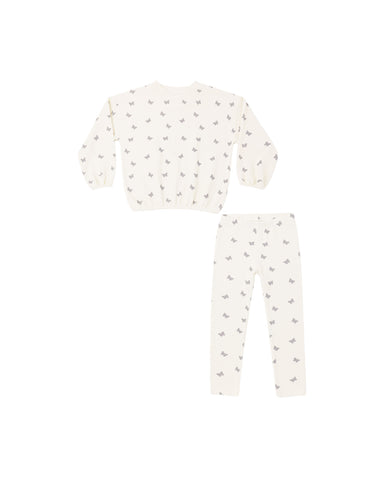A two-piece children's sweatsuit featuring a long-sleeve top and matching pants in a warm off-white/cream color, both printed with a small repeating gray pattern of birds or butterflies.