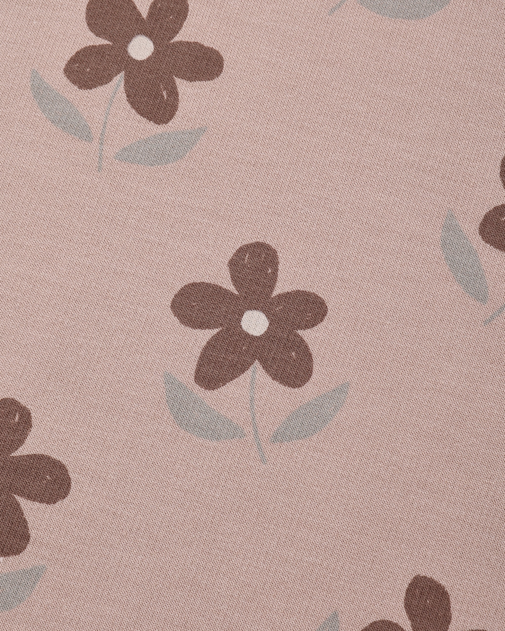 A close-up of a dusty pink fabric with a repeating pattern of dark brown flowers and light gray-green leaves.