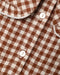 A close up of a brown and white gingham check pattern fabric, featuring buttons in the back
