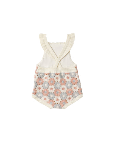 Baby romper with floral pattern and ruffled top on a white background
