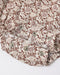 Close-up of a floral-patterned fabric garment, likely a skirt or shorts, featuring a brown and dusty pink floral print on a cream background with decorative metal snap buttons.