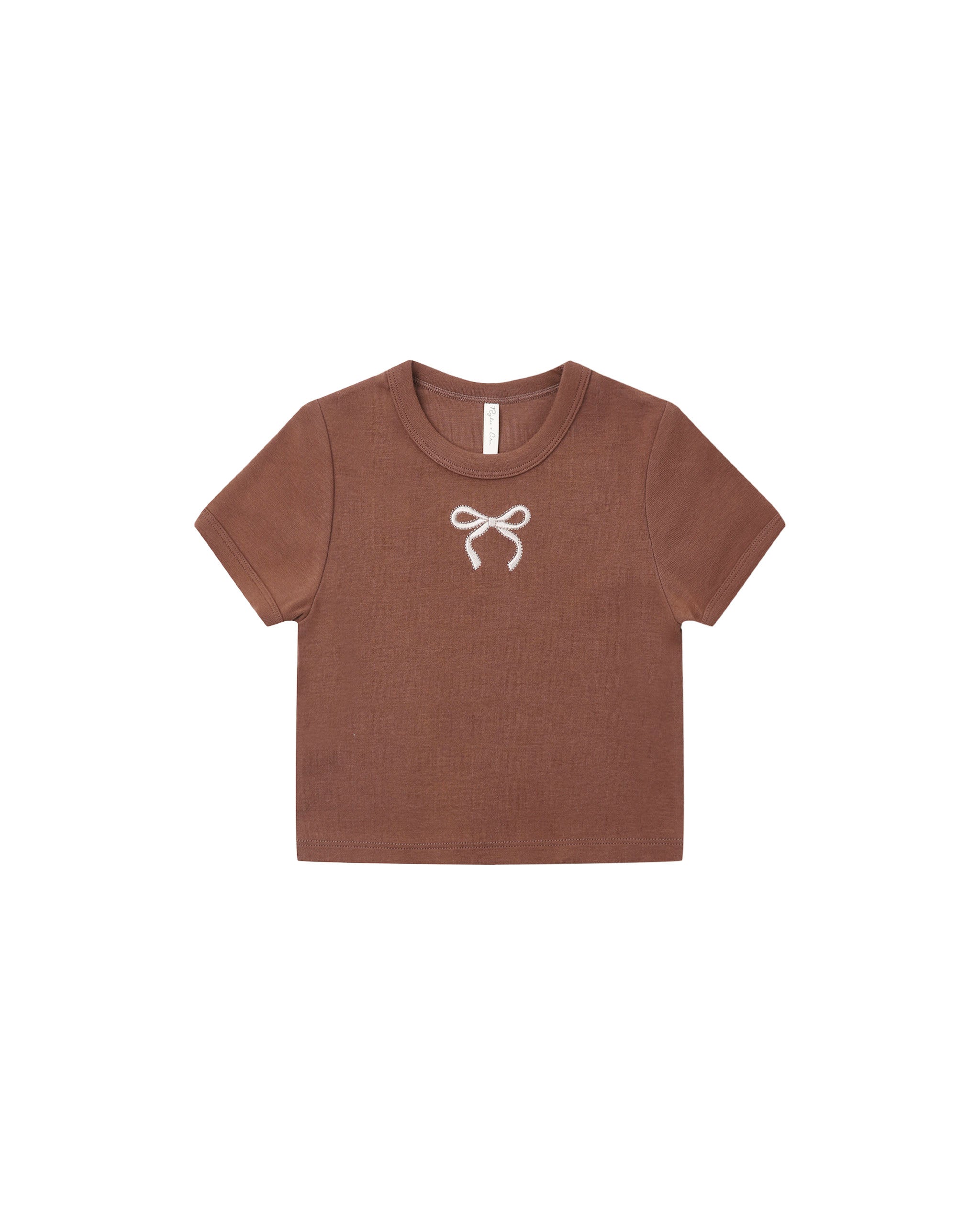 A brown short-sleeve crop top for kids, featuring a small white bow graphic on the center chest, displayed flat against a solid white background.