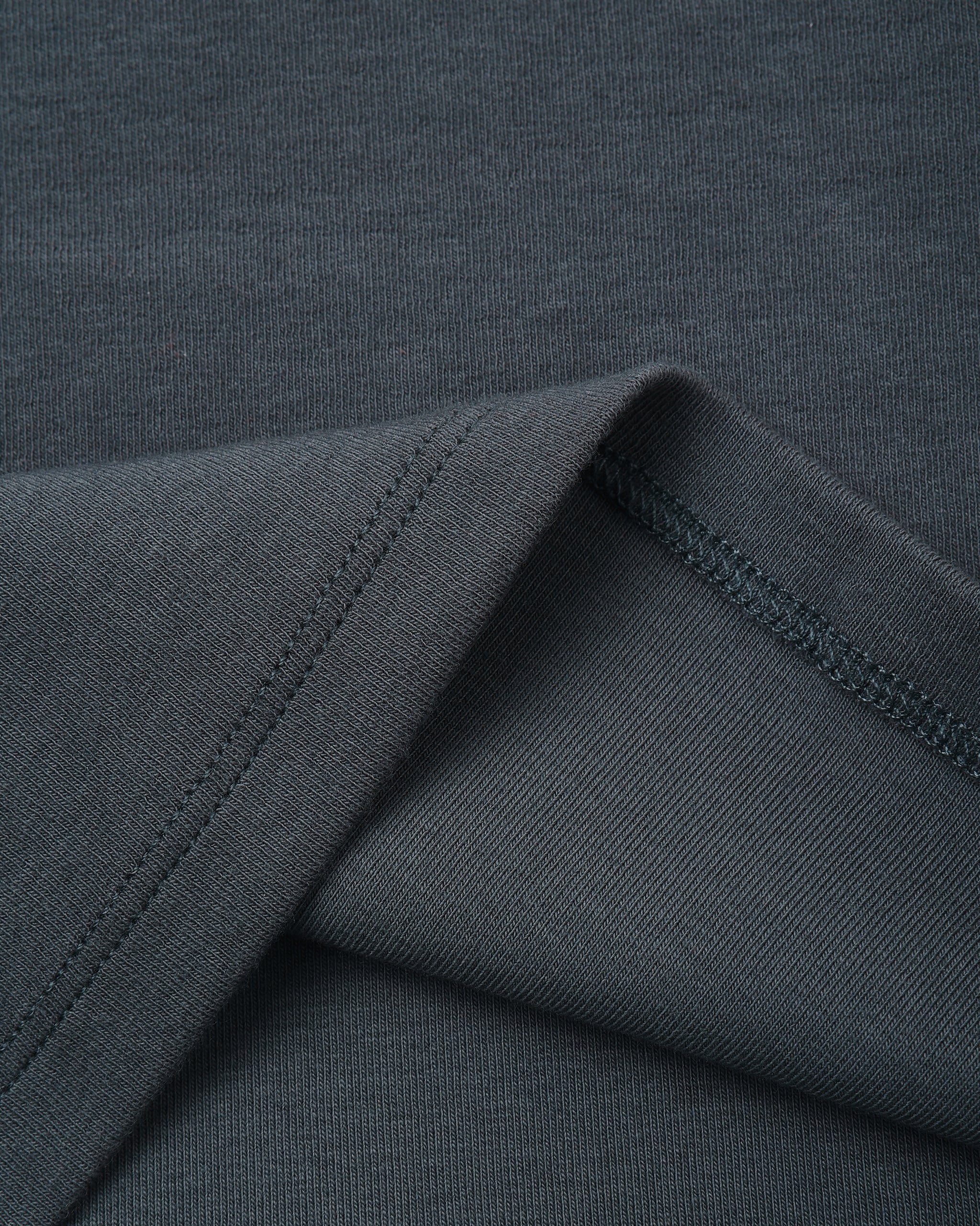 Close-up of a dark charcoal gray ribbed knit fabric with a folded corner showing the texture and stitching.