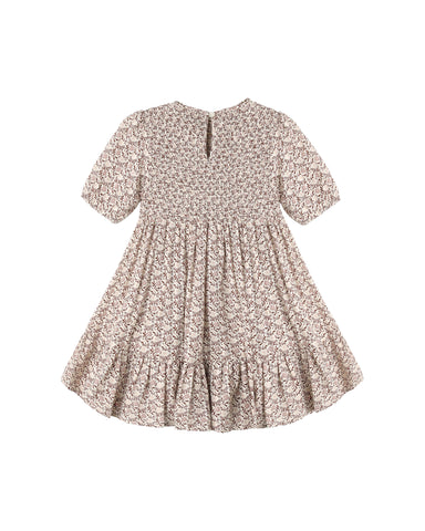 A short-sleeve baby dress with a dense beige and brown floral pattern, featuring a smocked bodice and a ruffled hem, shown flat against a white background.