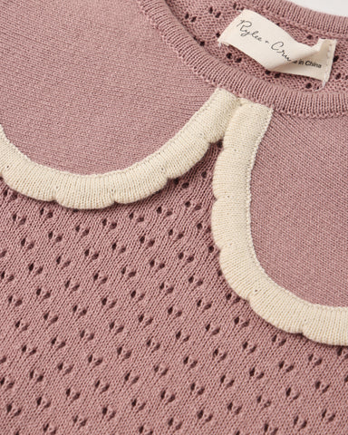 Close-up of a dusty pink knit sweater with a scalloped cream collar and a visible neck label reading 'Pylea - Copenhagen'.