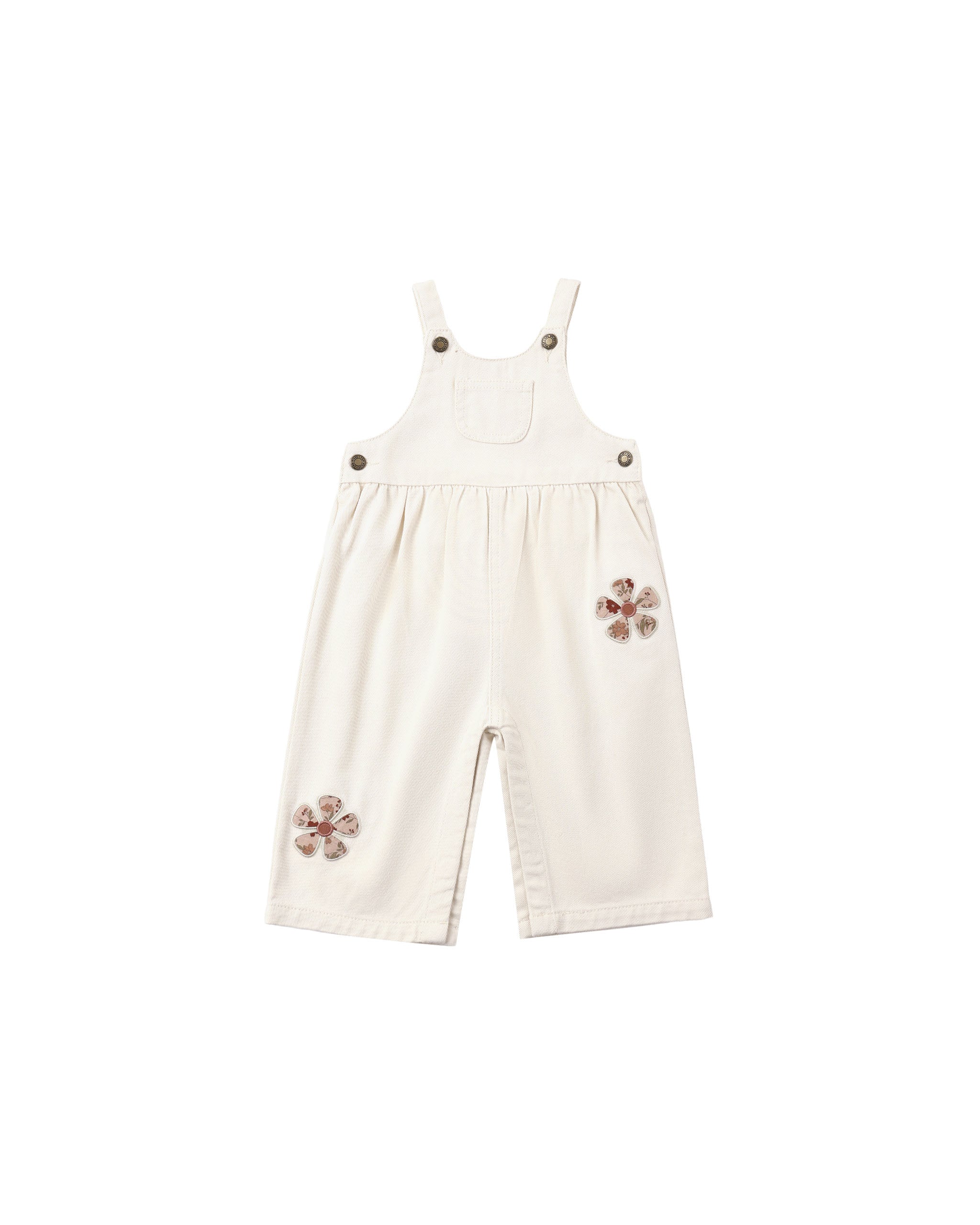 A natural colored denim overall with daisy patches applique shown  on a white background.