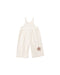 A natural colored denim overall with daisy patches applique shown  on a white background.