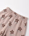 Close-up of a pair of light pink pants with an elastic waistband, featuring an all-over print of brown flowers with light blue-green leaves, shown on a plain white background.