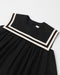 Black dress with white trim on a light gray background