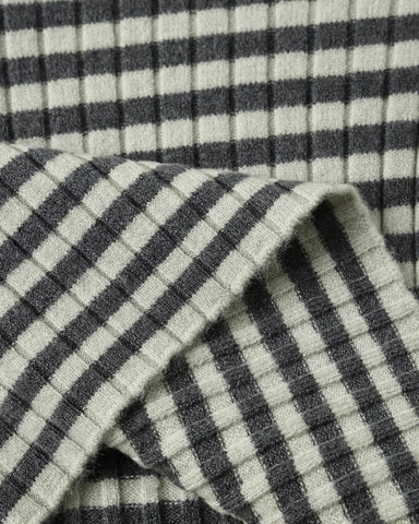 Close-up of a ribbed knit fabric with a dark black and white striped pattern, folded to show texture and weave.