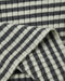 Close-up of a ribbed knit fabric with a dark black and white striped pattern, folded to show texture and weave.
