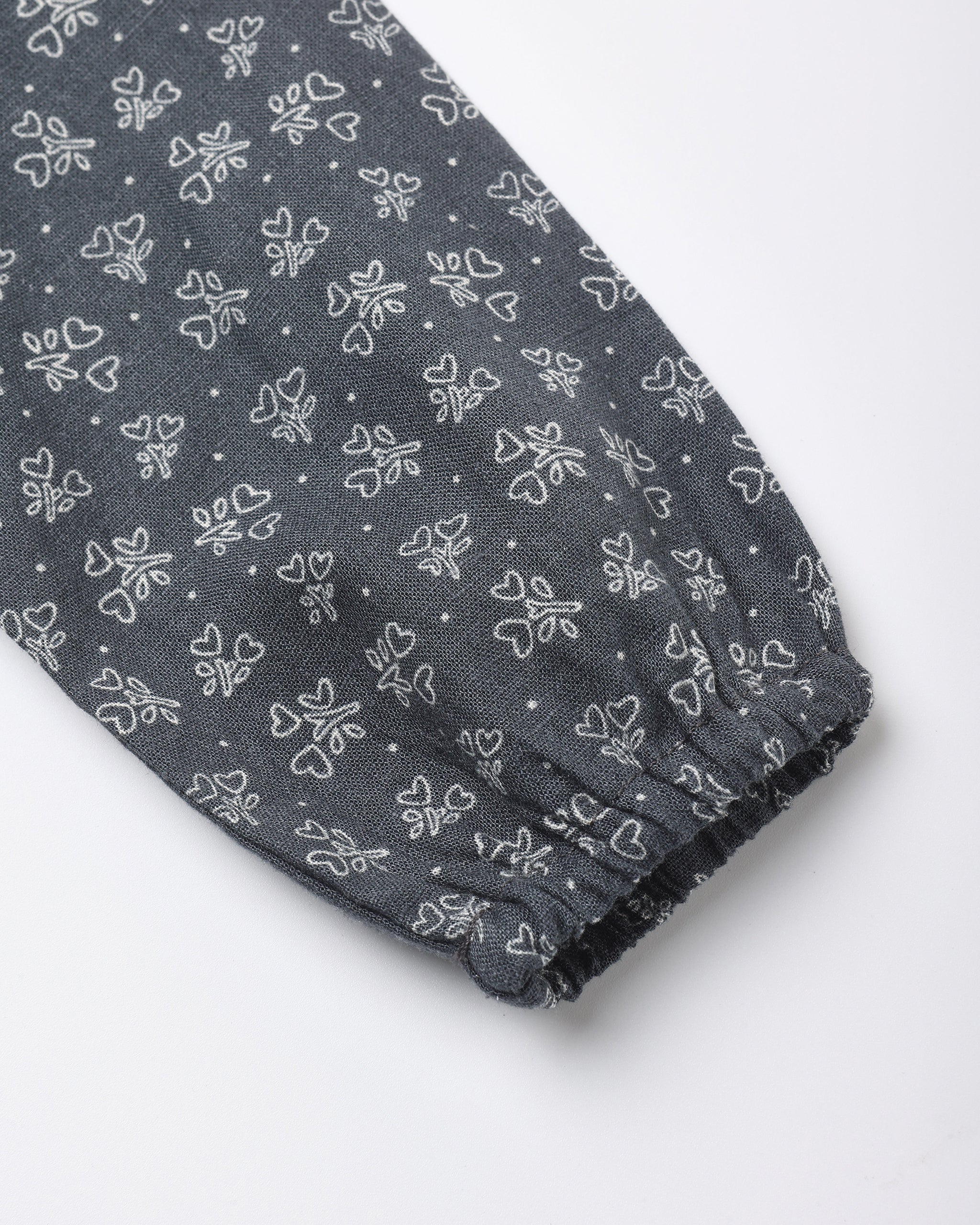 A close-up of a dark blue fabric sleeve or cuff with an all-over white bow and bow print pattern, finished with a gathered elastic hem.