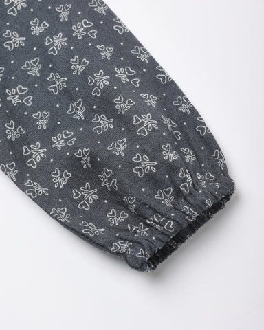 A close-up of a dark blue fabric sleeve or cuff with an all-over white bow and bow print pattern, finished with a gathered elastic hem.