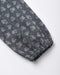 A close-up of a dark blue fabric sleeve or cuff with an all-over white bow and bow print pattern, finished with a gathered elastic hem.