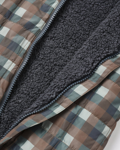 Close-up of a quilted puffer jacket with a brown, beige, and gray plaid patterned exterior and a dark gray sherpa fleece interior.