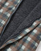 Close-up of a quilted puffer jacket with a brown, beige, and gray plaid patterned exterior and a dark gray sherpa fleece interior.