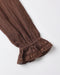 A close-up of a brown textured fabric sleeve with a gathered elastic cuff and decorative lace trim, shown on a plain light background.