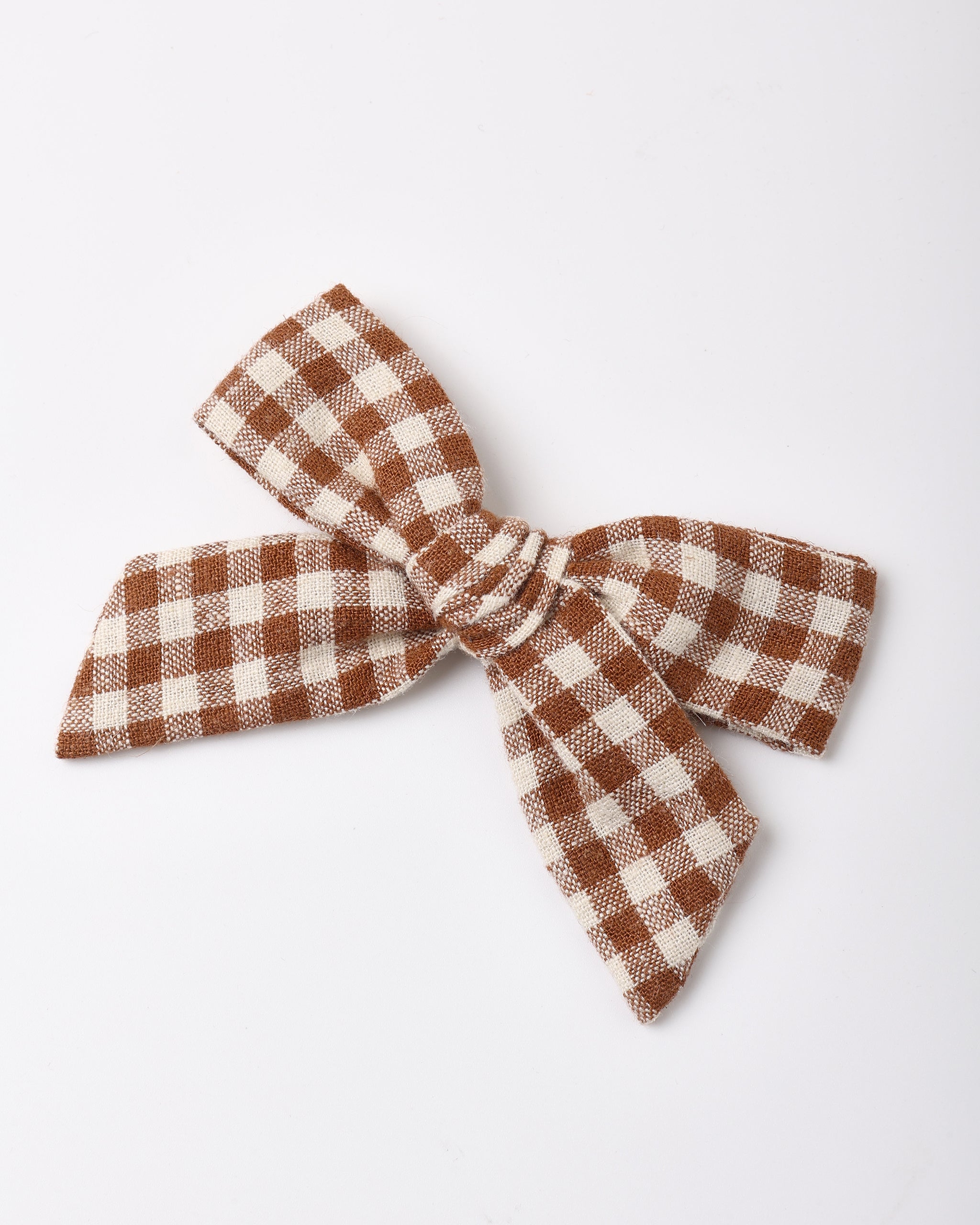 A fabric hair bow with a brown and cream gingham checkered pattern, photographed on a clean white background.