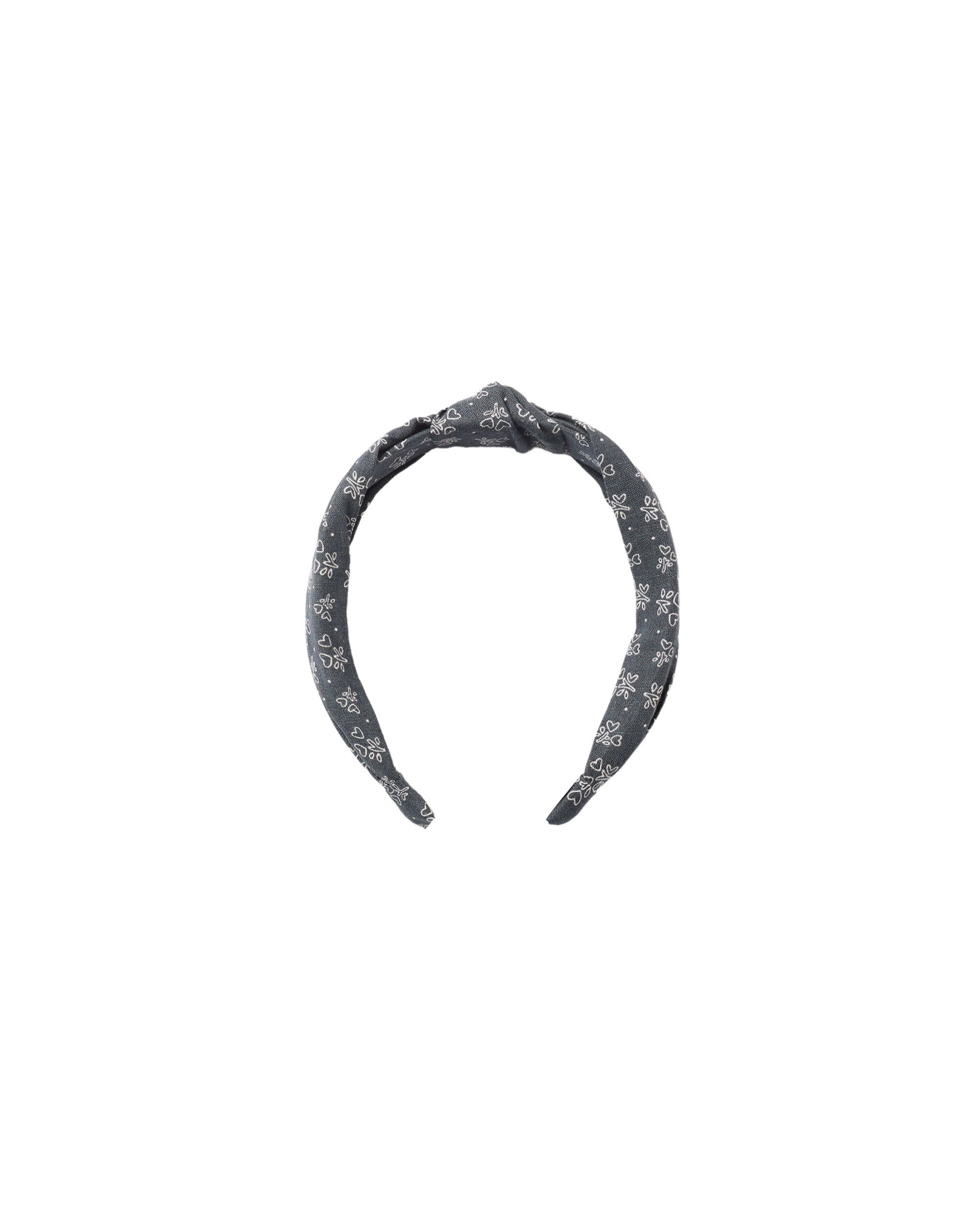 A dark gray fabric headband with a white floral pattern, featuring a knotted top detail, shown against a plain white background.