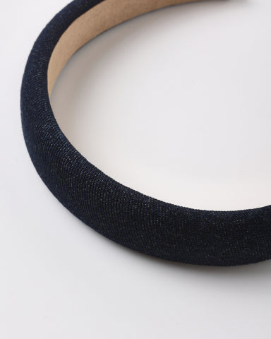A close-up of a dark navy blue fabric-covered headband with a light tan inner band, shown on a plain white background.