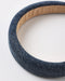 A close-up of a thick, ribbed fabric headband in a dark blue denim-like texture, showing a tan inner lining on a plain white background.