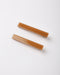 Two rectangular hair claw clips in a warm caramel brown translucent resin, displayed diagonally on a clean white background.