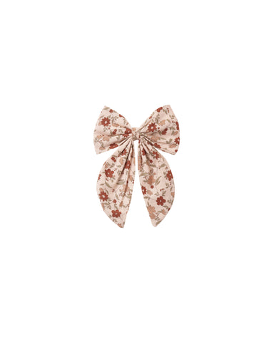 An oversized hair bow in a pink floral pattern attached to an alligator clip