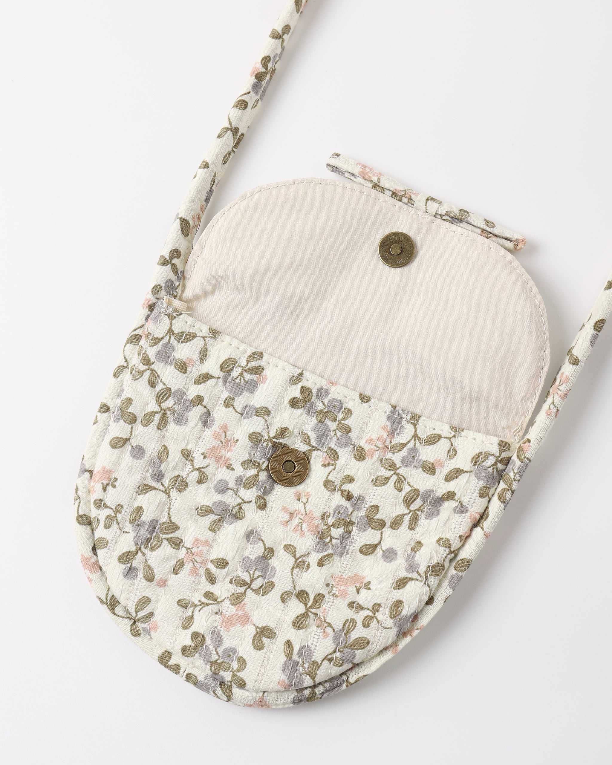 A small quilted crossbody bag with a floral patterned exterior and a solid cream-colored interior lining, featuring two metal snap buttons and a matching shoulder strap, shown on a plain white background.