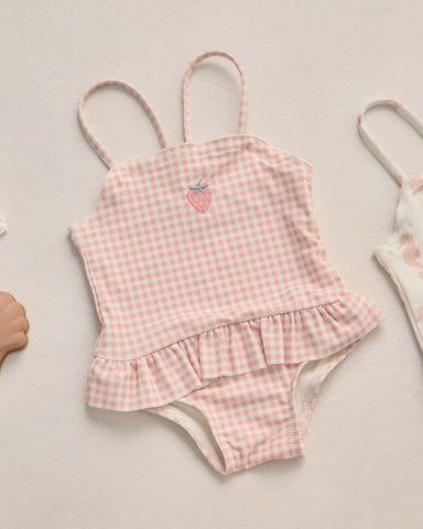 Pink gingham swimsuit with ruffle details on a light background