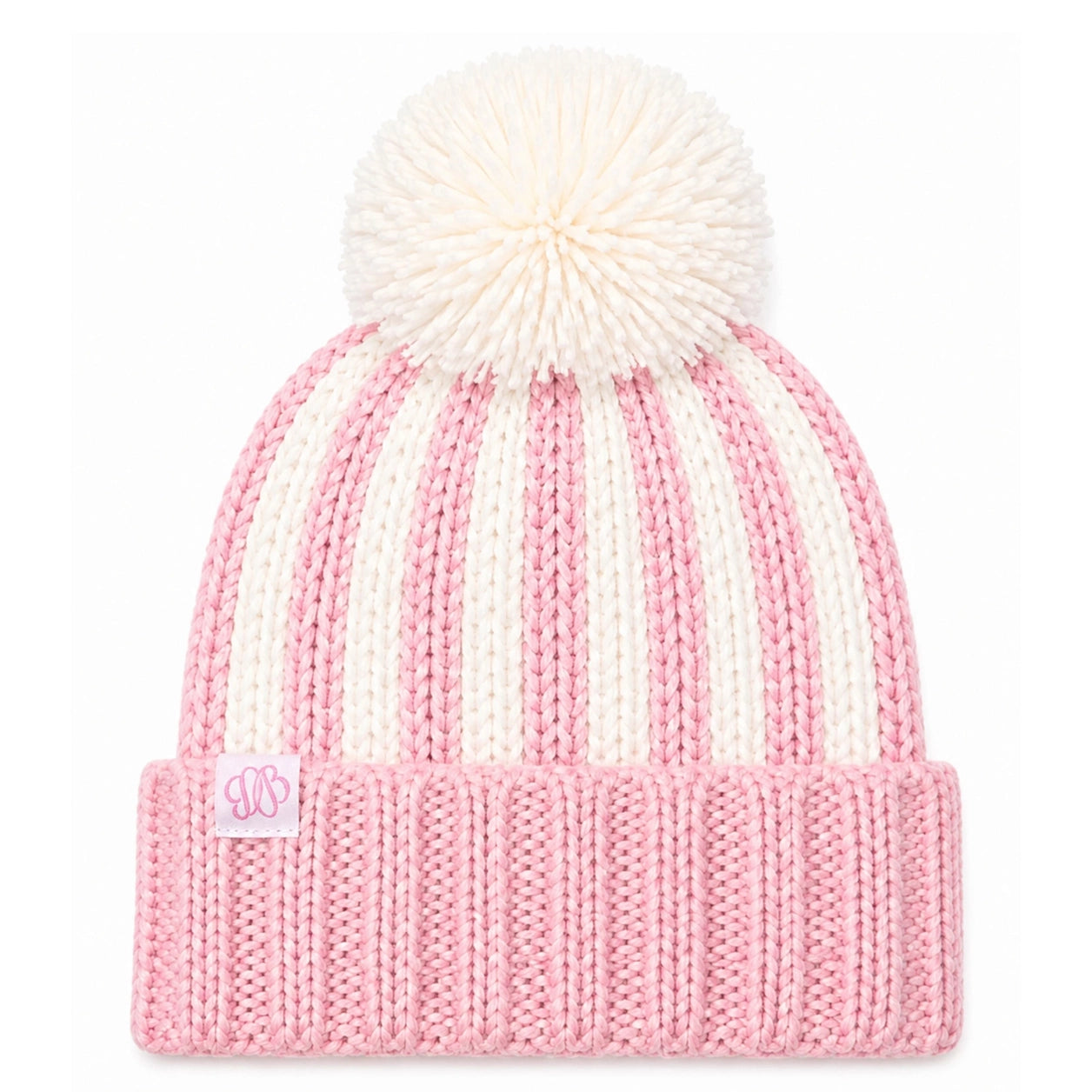 A pink and cream striped knit beanie with a large cream pom-pom on top and a folded ribbed cuff. A small embroidered monogram patch is visible on the cuff.