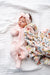 Newborn baby wrapped in a floral blanket on a white bed