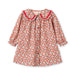 A long-sleeve button-front dress for toddlers, featuring a dense red, blue, and yellow floral print on a white background, with a contrasting red ruffled Peter Pan collar.