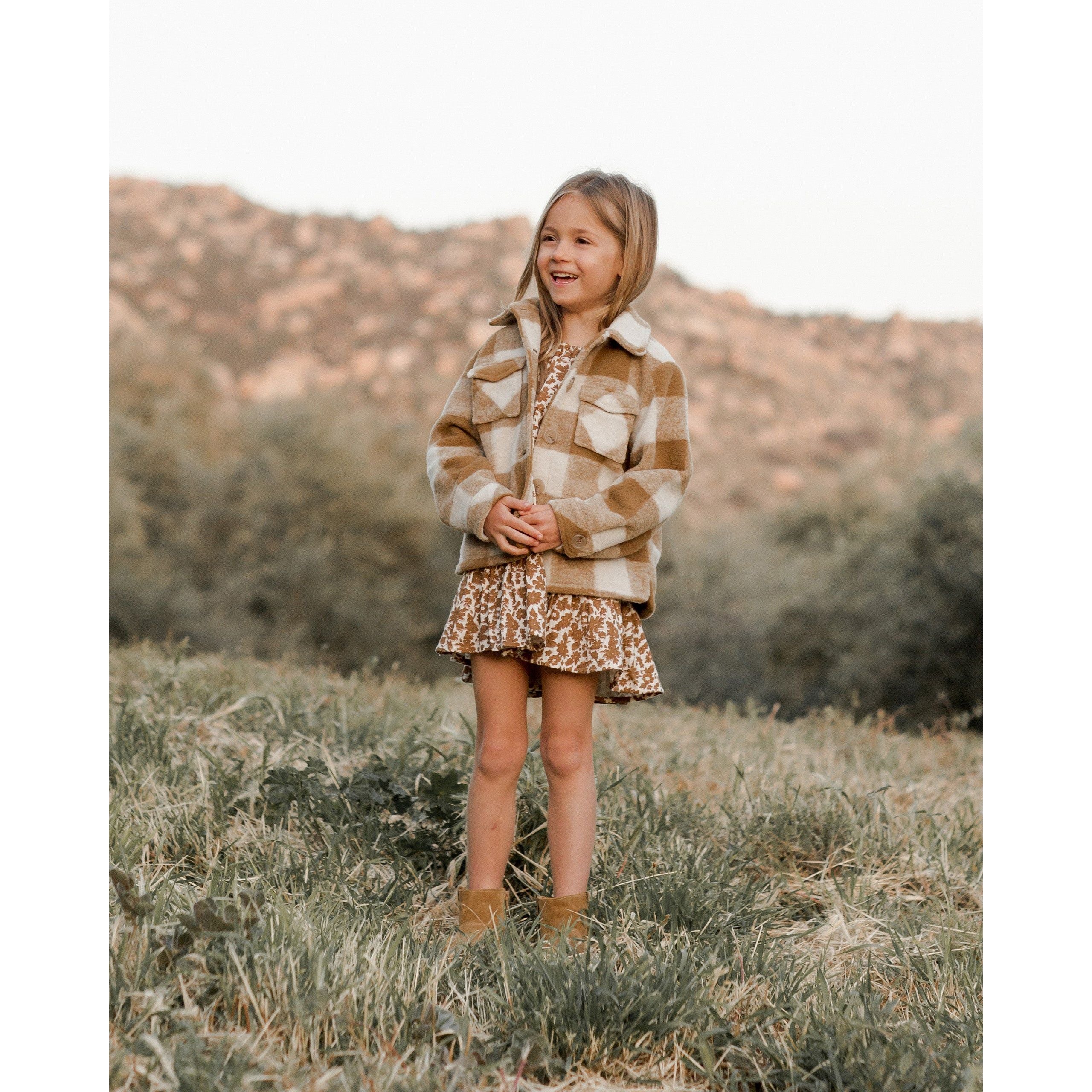 girl wearing chore coat in brass and white checkered pattern and buttons