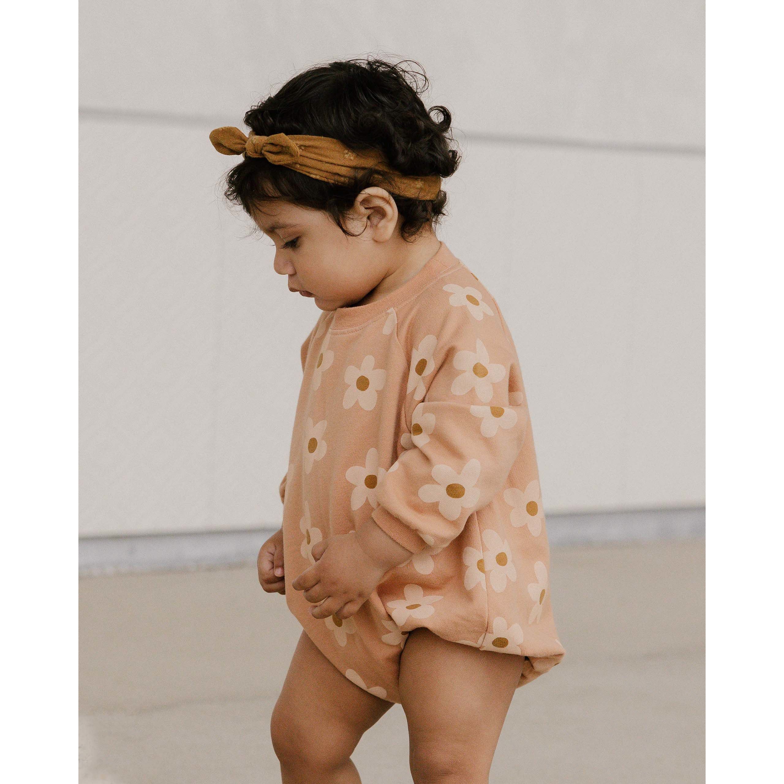 baby girl wearing light orange crewneck longsleeve bubble romper with daisy print
