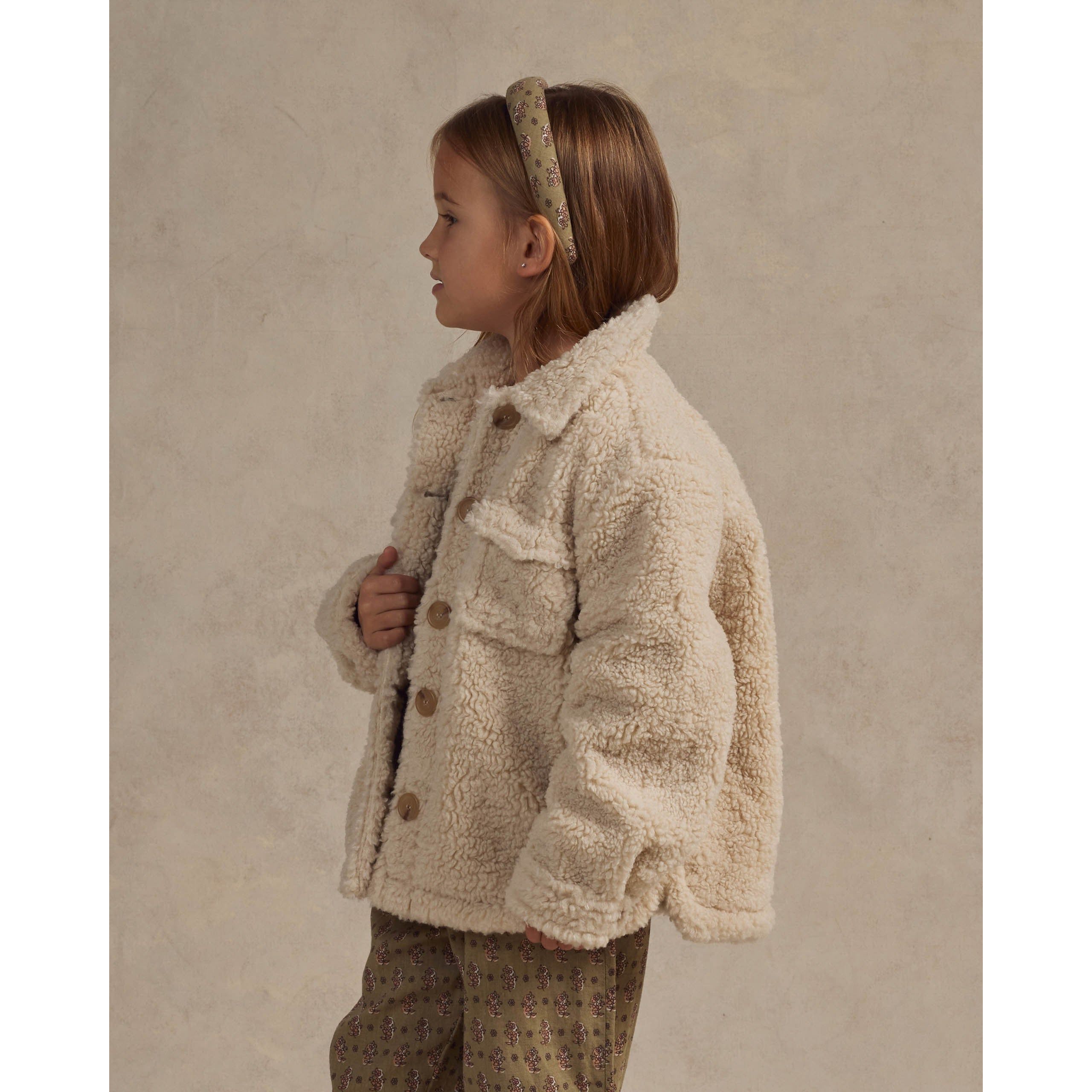 girl wearing cream colored fleece chore coat with buttons